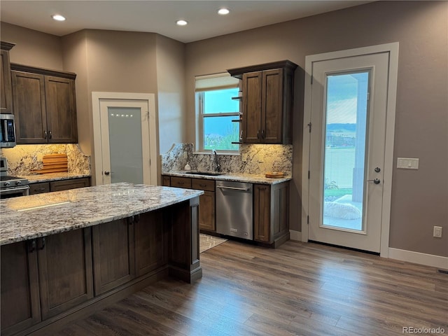 kitchen with dark brown cabinets, light stone counters, sink, and appliances with stainless steel finishes