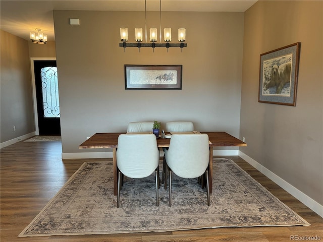 dining area with dark hardwood / wood-style floors and an inviting chandelier