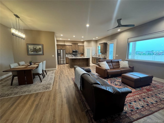 living room featuring hardwood / wood-style floors and ceiling fan with notable chandelier