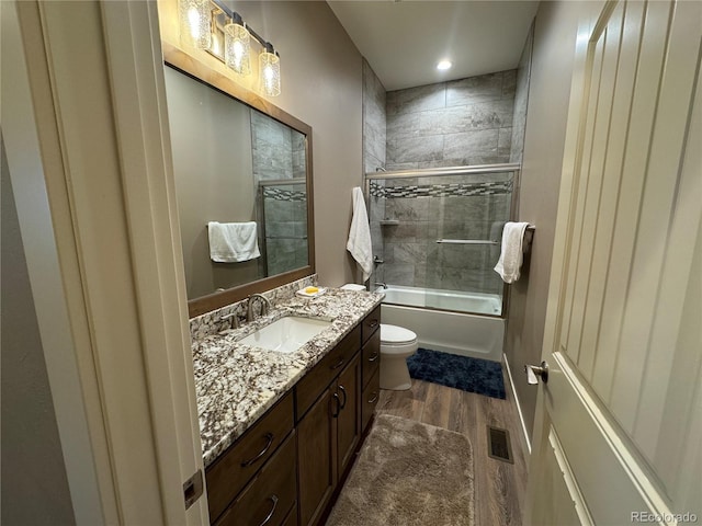 full bathroom featuring shower / bath combination with glass door, vanity, wood-type flooring, and toilet