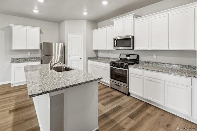 kitchen with sink, appliances with stainless steel finishes, a center island with sink, and hardwood / wood-style floors