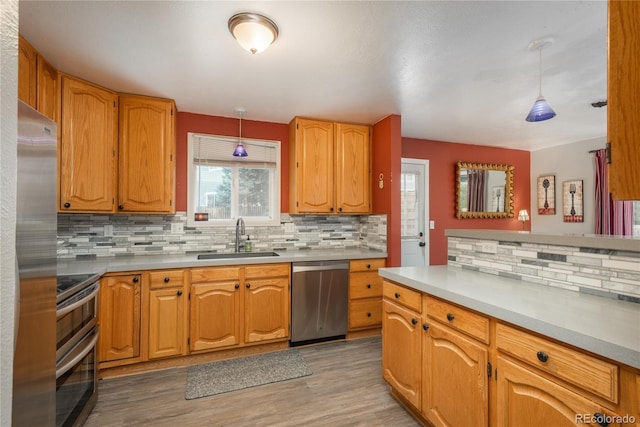 11805 W 74th Ave, Arvada, CO 80005 - kitchen featuring appliances with stainless steel finishes, backsplash, pendant lighting, and light wood finished floors