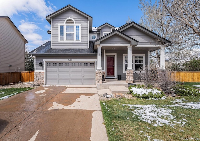 craftsman inspired home with an attached garage, driveway, stone siding, and fence