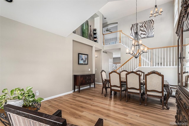interior space with baseboards, an inviting chandelier, a towering ceiling, and light wood-style flooring