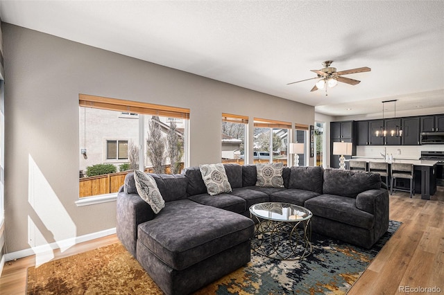 living area with ceiling fan, baseboards, and light wood-style floors