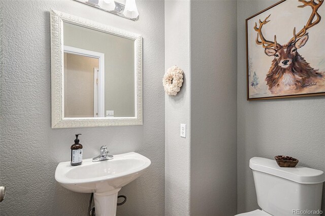 bathroom with a textured wall and toilet