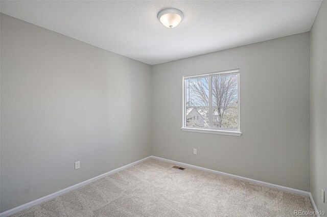 unfurnished room featuring carpet, visible vents, and baseboards