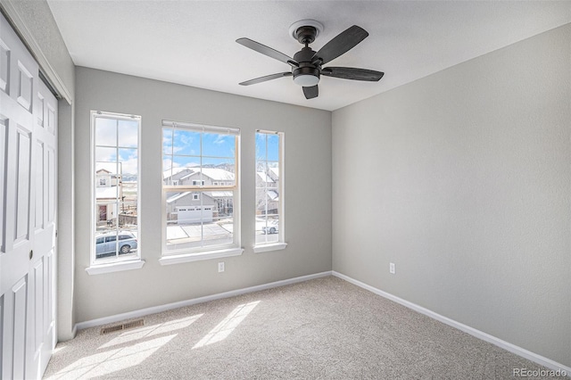 empty room featuring ceiling fan, baseboards, visible vents, and carpet