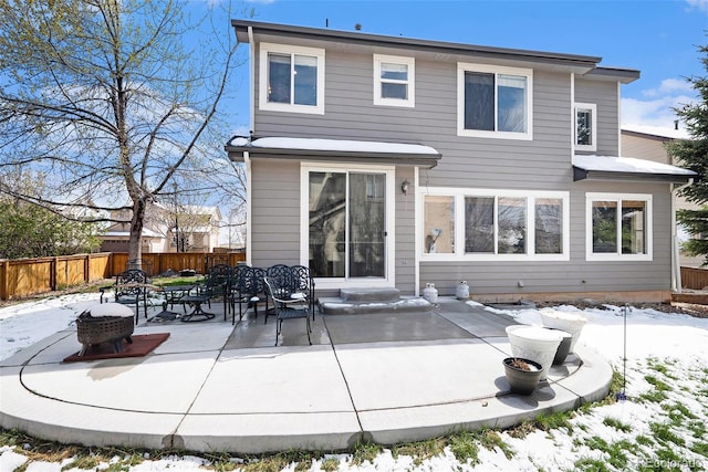 snow covered rear of property featuring fence and a patio