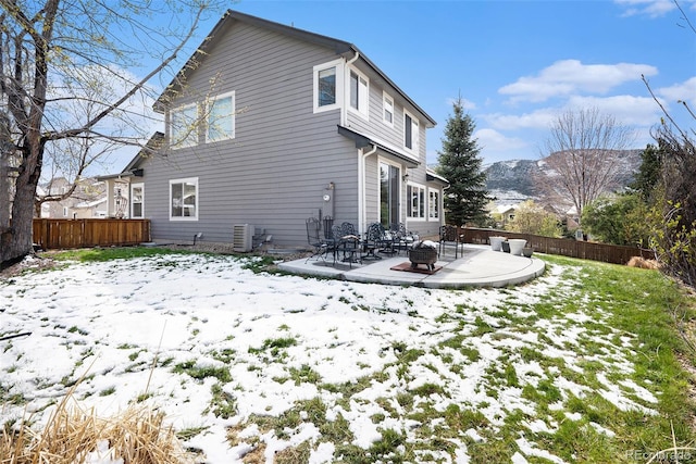 snow covered property with fence, central air condition unit, and a patio