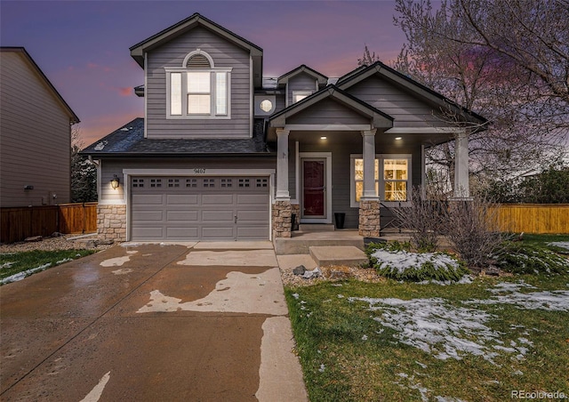 view of front of property featuring concrete driveway, stone siding, an attached garage, fence, and a porch
