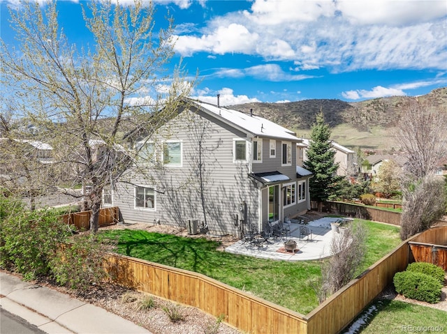 view of property exterior with a fenced backyard, central AC unit, a mountain view, a patio area, and a lawn