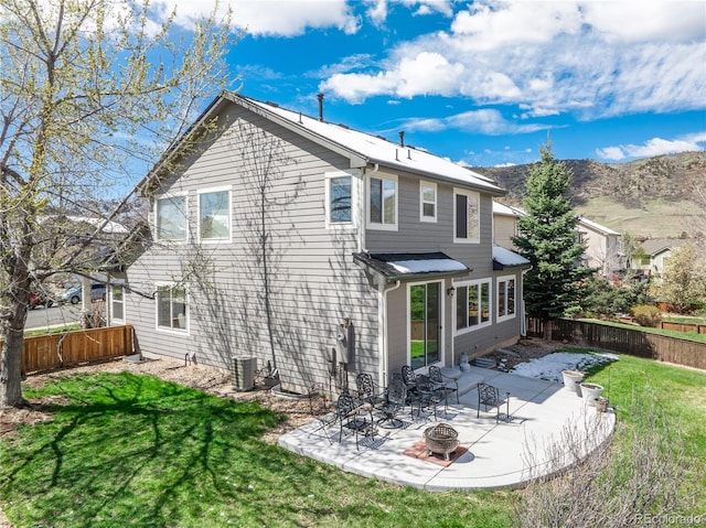 rear view of property featuring a lawn, a fenced backyard, a patio, and an outdoor fire pit