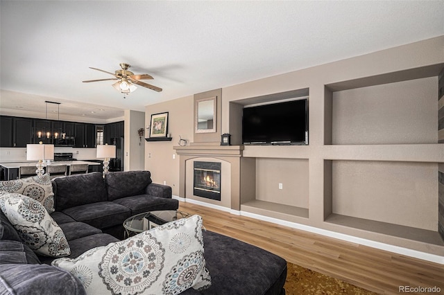 9407 W Gibraltar Pl, Littleton, CO 80127 - living area featuring a glass covered fireplace, light wood-type flooring, and a ceiling fan