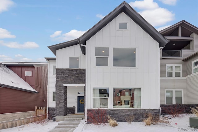 view of front of house with stone siding, fence, and board and batten siding