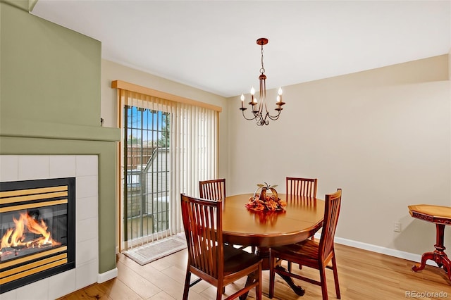 dining space featuring a chandelier, a tile fireplace, and light hardwood / wood-style flooring