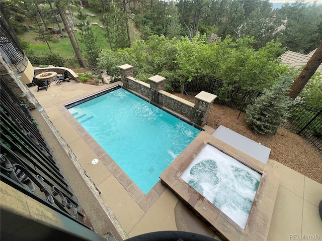 view of swimming pool with an in ground hot tub and an outdoor fire pit