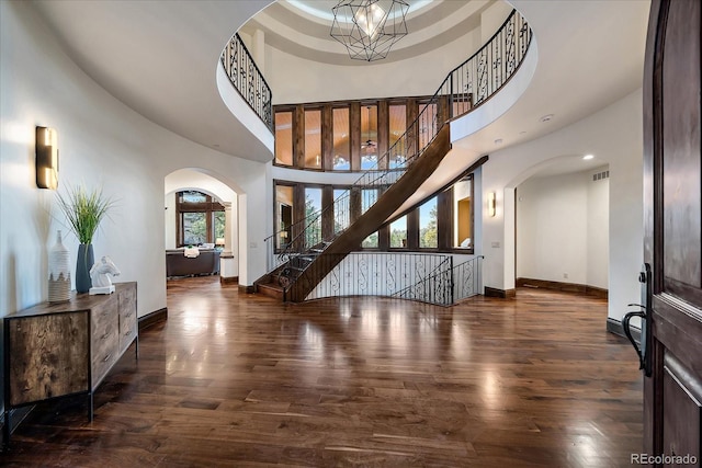 entryway featuring a notable chandelier, dark hardwood / wood-style flooring, and a towering ceiling