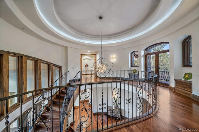 hallway with french doors, dark hardwood / wood-style flooring, an inviting chandelier, and a raised ceiling