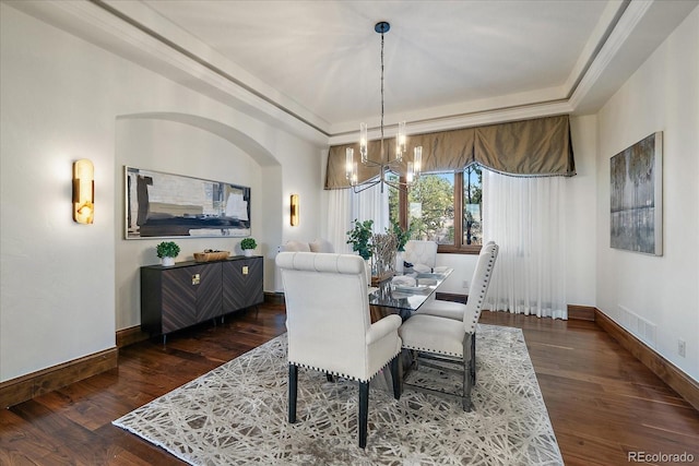 dining space featuring dark hardwood / wood-style floors, an inviting chandelier, and a tray ceiling