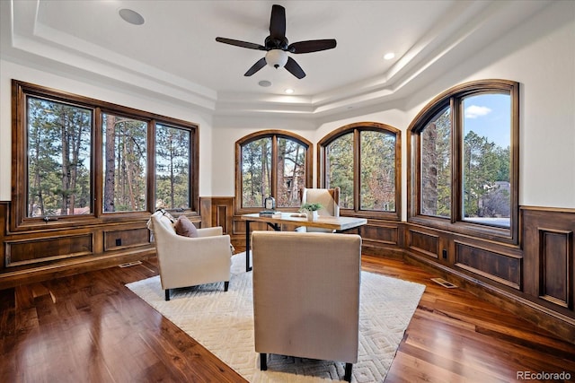 sitting room with a tray ceiling, ceiling fan, and wood-type flooring