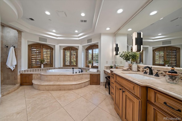 bathroom featuring tile patterned flooring, vanity, plus walk in shower, and a tray ceiling