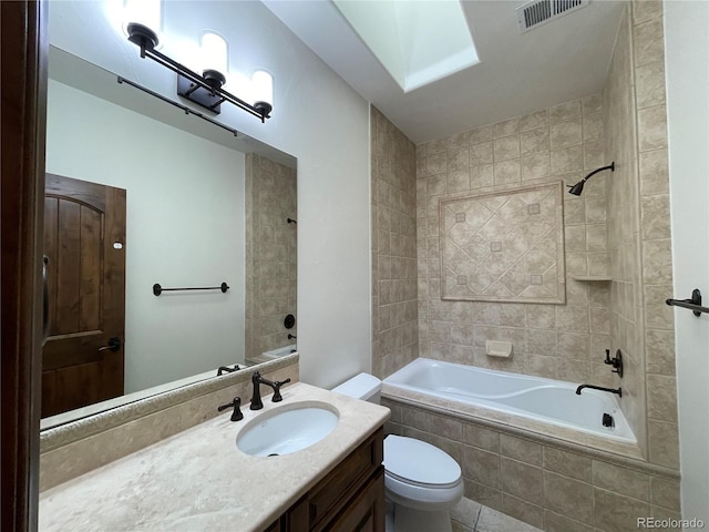 full bathroom featuring a skylight, vanity, tiled shower / bath combo, and toilet