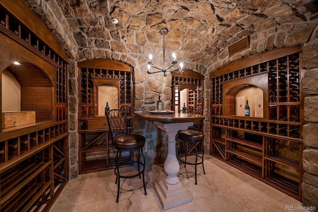 wine cellar with a notable chandelier, lofted ceiling, and brick ceiling