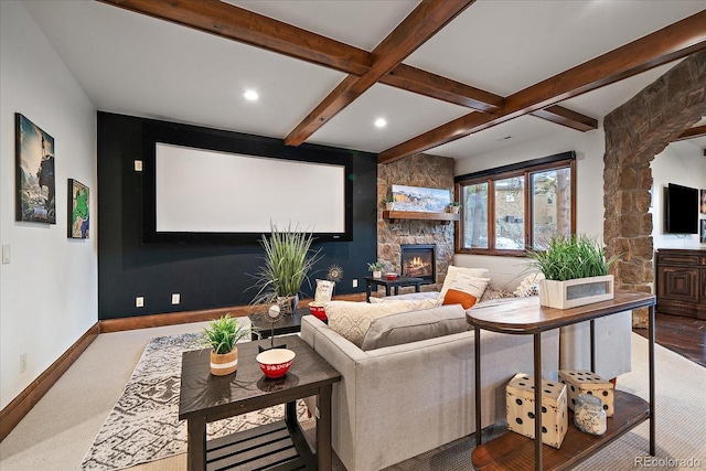 cinema featuring beamed ceiling, carpet, a stone fireplace, and coffered ceiling