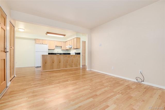 unfurnished living room featuring a sink, baseboards, and light wood-style flooring