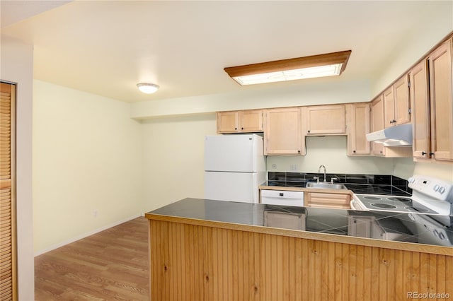kitchen with a sink, white appliances, a peninsula, light wood-type flooring, and under cabinet range hood