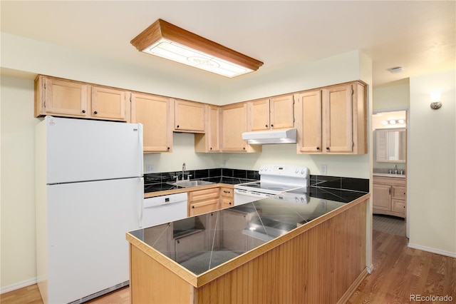 kitchen featuring a peninsula, under cabinet range hood, light brown cabinets, and white appliances