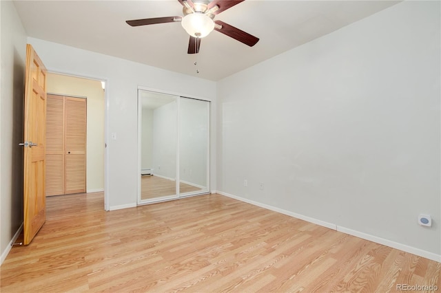 unfurnished bedroom with baseboards, a baseboard heating unit, light wood-style flooring, and a closet