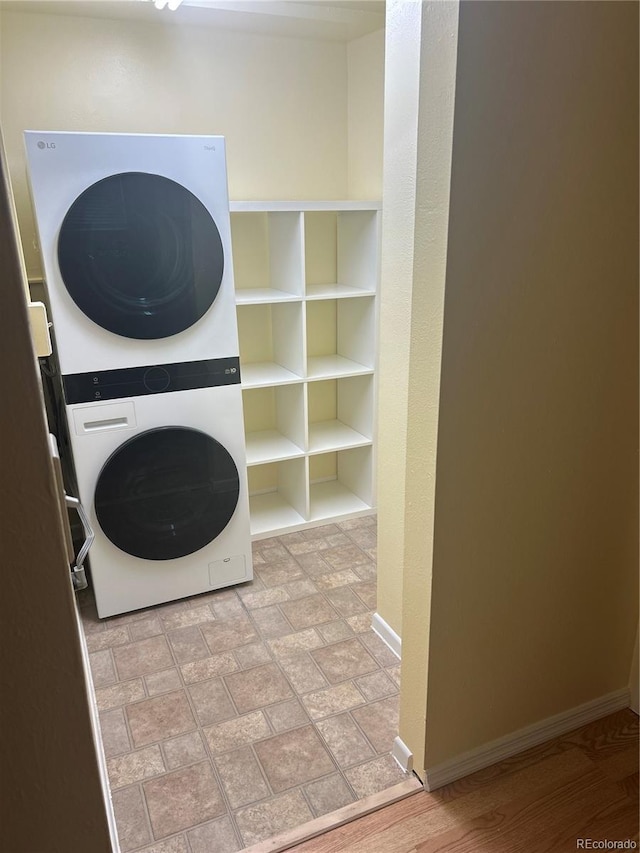 laundry area with baseboards, stacked washer / drying machine, and laundry area
