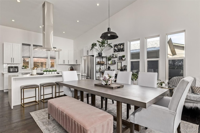 dining space featuring a towering ceiling and dark hardwood / wood-style floors