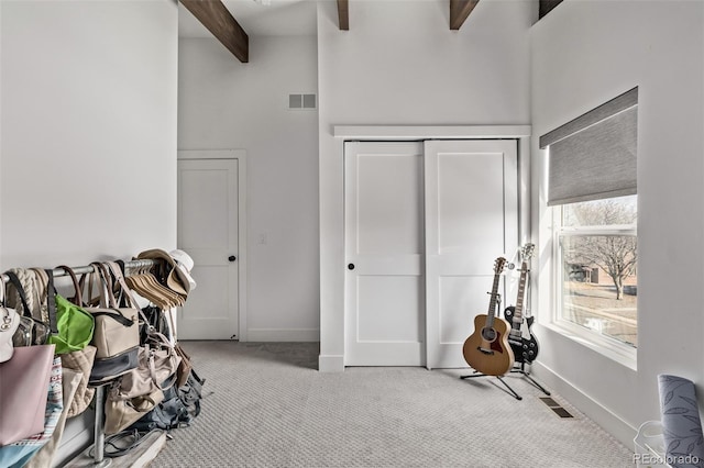 interior space featuring a towering ceiling, beam ceiling, and light carpet