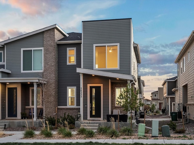 contemporary home with a porch and brick siding