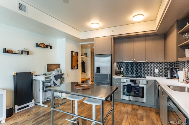 kitchen with dark hardwood / wood-style flooring, backsplash, sink, and appliances with stainless steel finishes