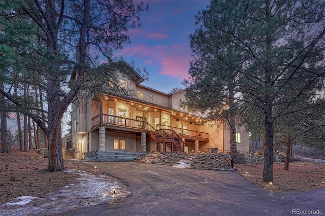 view of front facade featuring driveway, stairs, and stucco siding