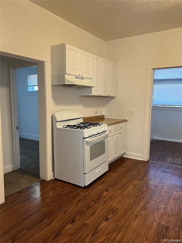 kitchen with white gas range oven, dark wood-type flooring, white cabinetry, and a healthy amount of sunlight