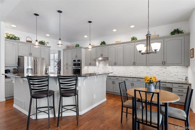 kitchen with gray cabinetry, hanging light fixtures, appliances with stainless steel finishes, and a kitchen island