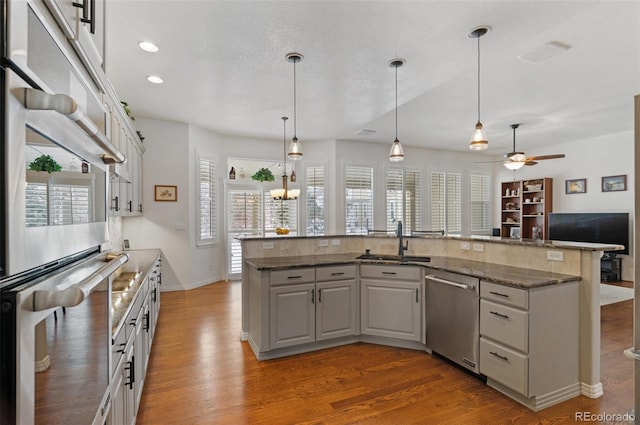 kitchen featuring gray cabinets, hardwood / wood-style floors, pendant lighting, sink, and stainless steel appliances