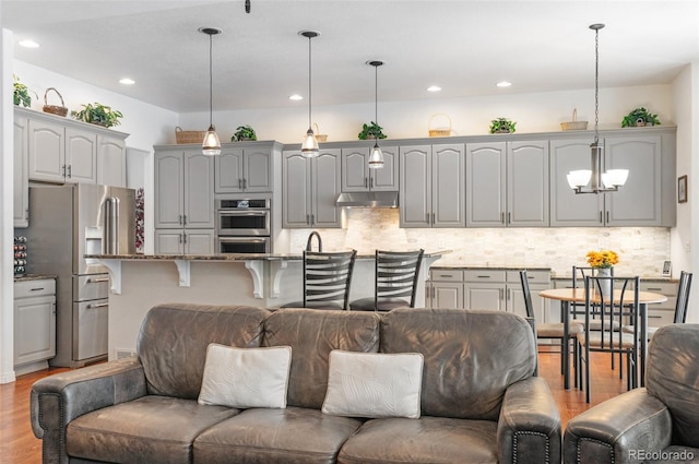 kitchen with stainless steel appliances, gray cabinetry, pendant lighting, and decorative backsplash