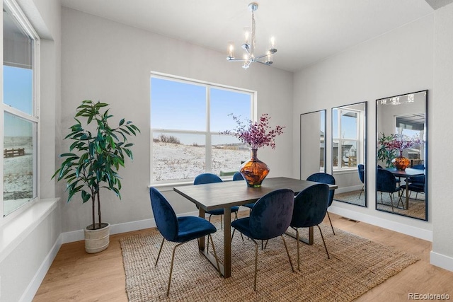 dining room with light wood-style flooring, visible vents, a chandelier, and baseboards