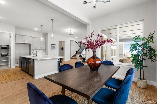 dining room featuring light wood-type flooring, baseboards, stairway, and recessed lighting