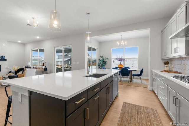 kitchen featuring light wood-style flooring, light countertops, a sink, and backsplash