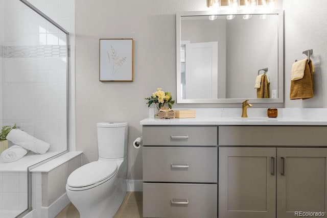 full bathroom featuring toilet, baseboards, a tile shower, and vanity