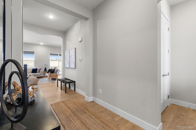 hall with baseboards and light wood finished floors