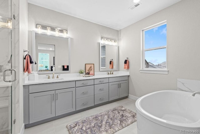 full bathroom with double vanity, a stall shower, visible vents, and a sink