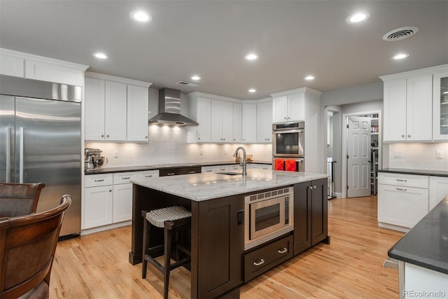 5164 E Princeton Ave, Cherry Hills Village, CO 80113 - kitchen with wall chimney range hood, tasteful backsplash, a sink, white cabinets, and built in appliances